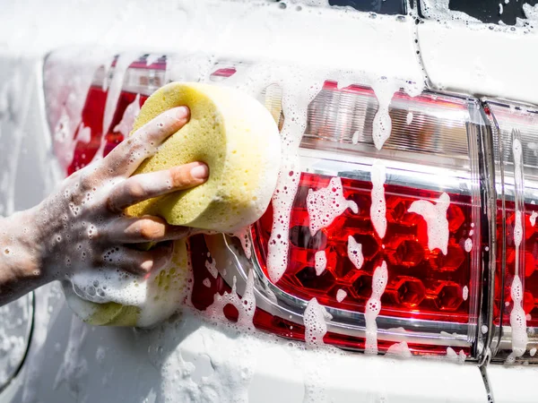 Woman hand with yellow sponge washing car — Stock Photo, Image