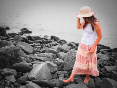 denize yakın kaya sahilde yürüyen güzel genç kadın