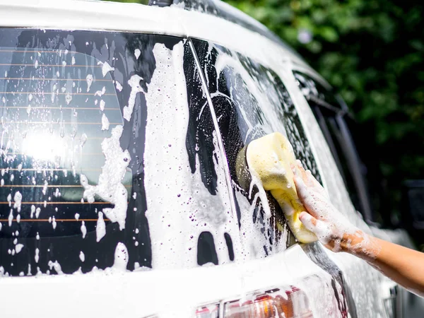 車を洗う黄色いスポンジで女性の手 — ストック写真