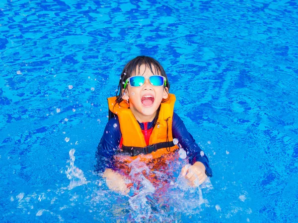 Niño feliz con chaleco salvavidas naranja se divierte y disfruta en la piscina —  Fotos de Stock