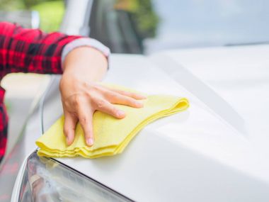 Sarı mikrofiber temizlik bezi ile beyaz el Otomobil.