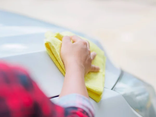 Mano con tela de microfibra amarilla limpieza coche blanco . — Foto de Stock