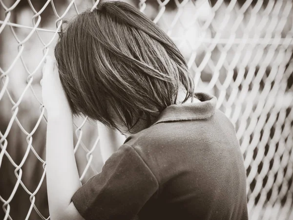 Black and white of handsome sad boy holding fence mesh netting. — Stock Photo, Image