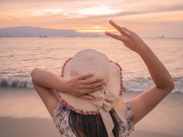 Женщина держит два пальца или Знак Победы на пляже во время заката, показывая ободрение, когда мы обескуражены . — стоковое фото