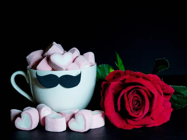 Conceito de dia do pai. com rosa vermelha e doce marshmallow na forma de coração em uma xícara de chá com bigode preto no fundo escuro — Fotografia de Stock