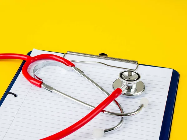 Estetoscopio con portapapeles sobre fondo amarillo para el médico que trabaja en el hospital escribiendo una receta médica , — Foto de Stock