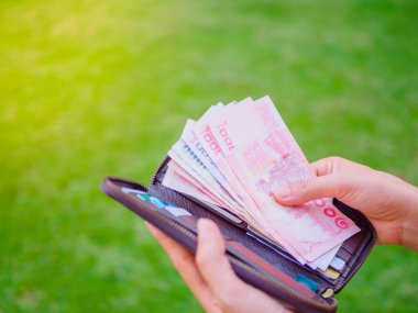 Kadınların elleri yeşil çim sahada cüzdanından para Tayland Bahtı yaptırmayı