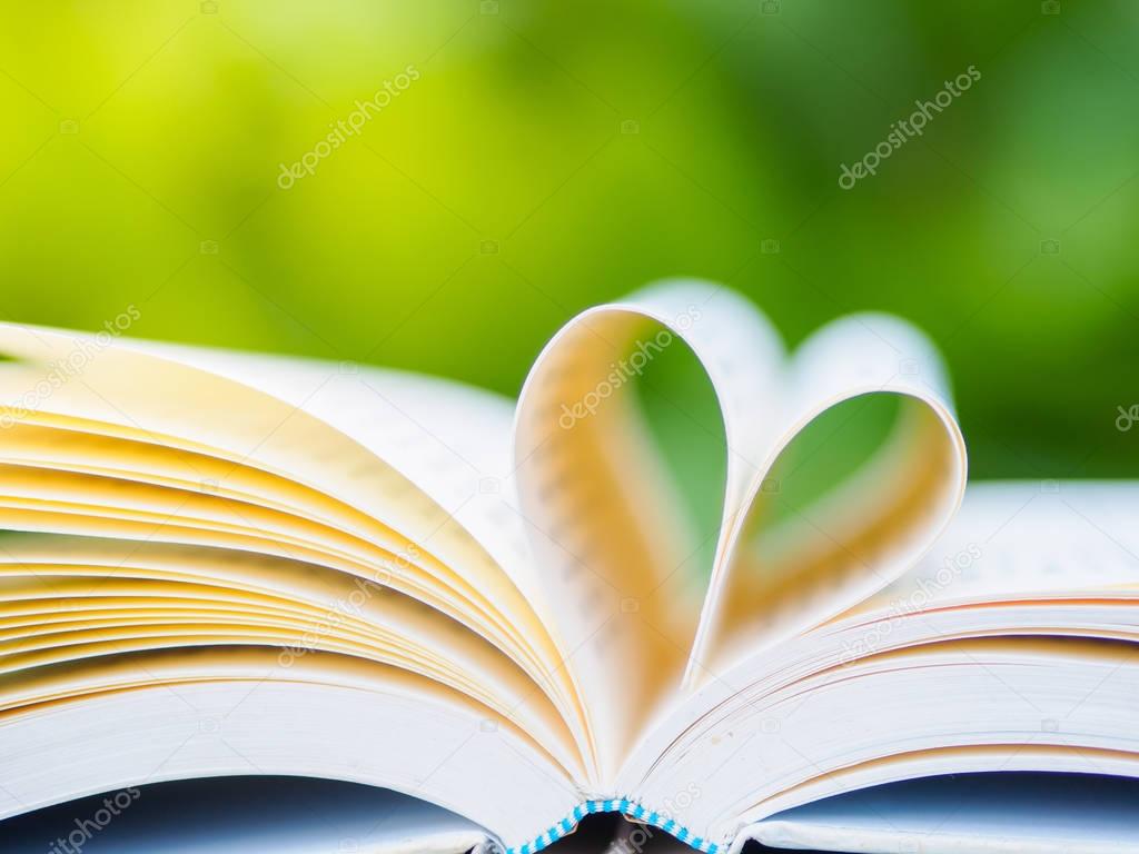 book on table in garden with top one opened and pages forming heart shape