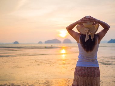 Kadın şapkası güneşin altında Kollarını açarak denize yakın