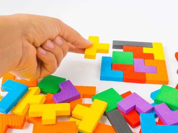 Mano sosteniendo la última pieza para completar un rompecabezas cuadrado tangram rompecabezas de madera colorido para el niño sobre fondo blanco — Foto de Stock