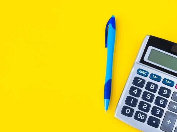 Flach liegend, Schreibtischgestell von oben. femininer Schreibtisch-Arbeitsplatz mit Büroaccessoires wie Taschenrechner und blauem Stift auf gelbem Hintergrund. — Stockfoto