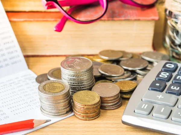 Ahorro de dinero abstracto. estado financiero con pila de monedas, calculadora y lápiz sobre mesa de madera con pila de libros y vasos . — Foto de Stock