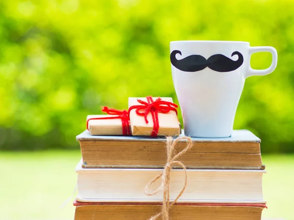 Conceito de dia do pai. Preto e branco de pilha de livros, presentes, xícara de chá com bigode preto e flor no fundo — Fotografia de Stock