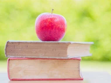 Dünya kitap günü kavramı. Kırmızı elma ve eski kitaplar yığında koymak kalem