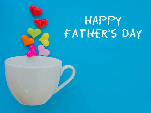 Concepto del día del padre. FELIZ DÍA DEL PADRE texto con corazón colorido en taza blanca y regalo sobre fondo azul — Foto de Stock
