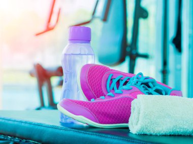 Pembe spor çifti havlu su şişesi fitness aletleri arka plan ile fitness odasında ayakkabılar. Spor ve egzersiz çalıştırmak için aksesuarlar.