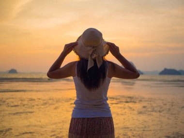 Kadın şapkası güneşin altında Kollarını açarak denize yakın