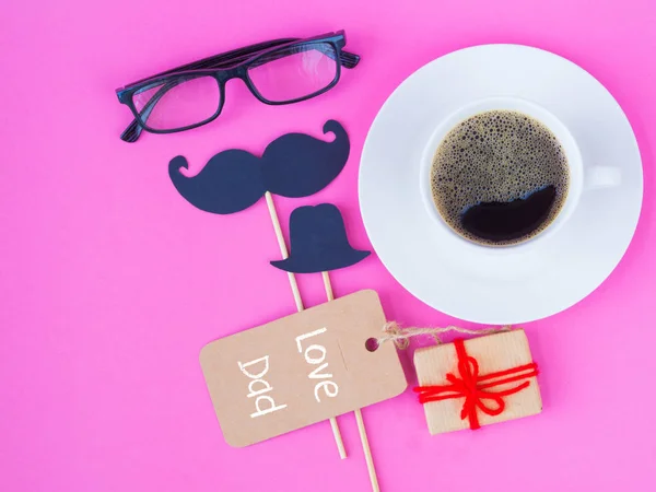 Conceito de dia do pai. AMOR mensagem DAD com flor rosa, óculos pretos, xícara de café, presente e bigode preto no fundo rosa — Fotografia de Stock