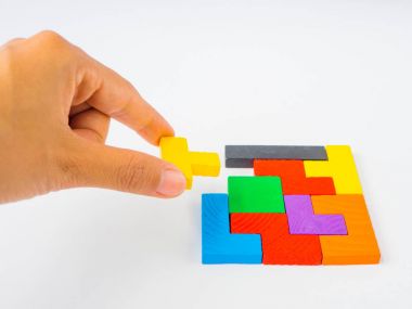Beyaz arka plan üzerinde çocuk için bir kare tangram bulmacanın renkli ahşap Bulmacayı tamamlamak için son parça tutan el