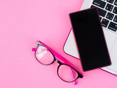 Smartphone üstten görünüm pembe bir arka plan üzerinde laptop ve pembe gözlük