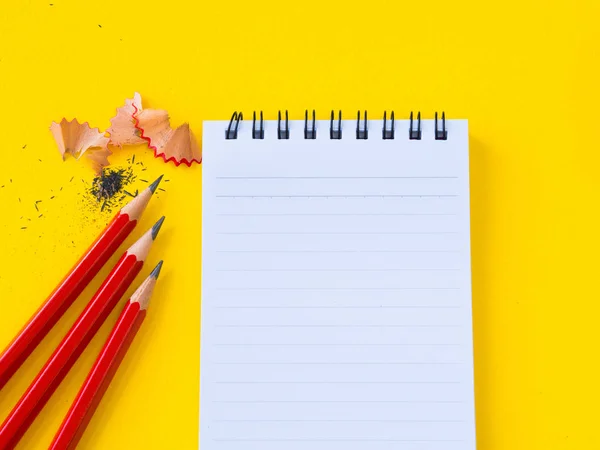 Kırmızı bir kalemtıraş ve Sarı zemin üzerine not defteri keskinleştirme. — Stok fotoğraf
