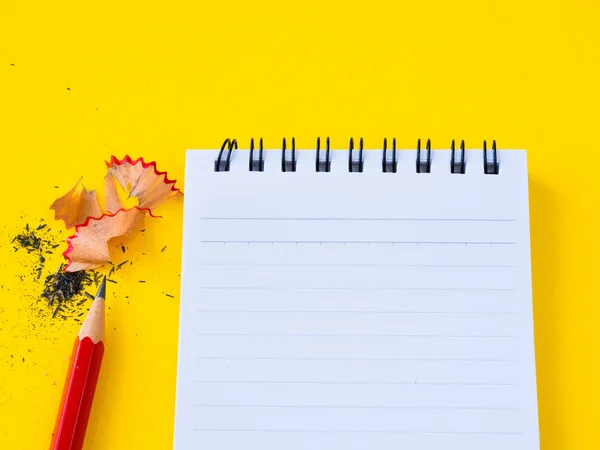 Kırmızı bir kalemtıraş ve Sarı zemin üzerine not defteri keskinleştirme. — Stok fotoğraf