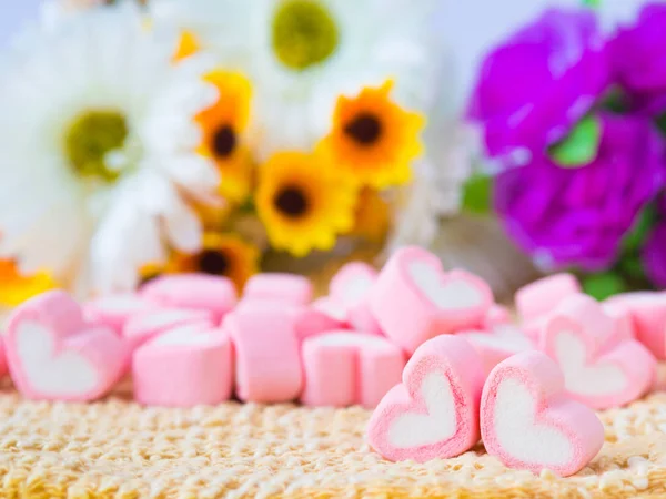 Primo piano di dolce marshmallow a forma di cuore su piatto di legno e fiore sullo sfondo . — Foto Stock