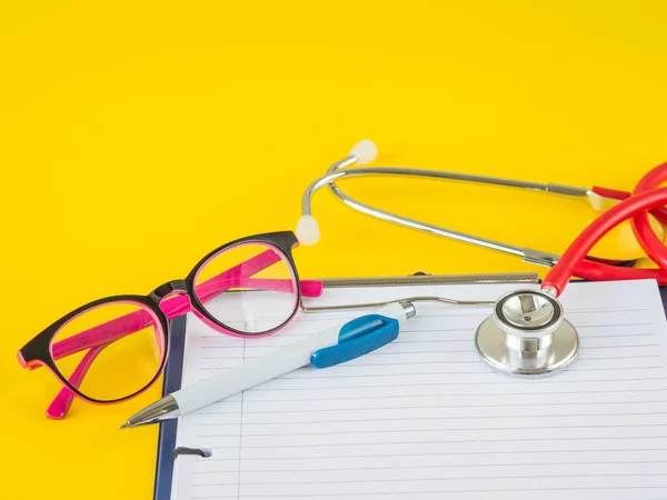 Estetoscopio con portapapeles, bolígrafo y gafas sobre fondo amarillo para el médico que trabaja en el hospital escribiendo una receta médica, Salud y concepto médico — Foto de Stock