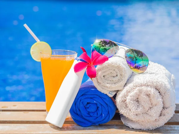 Flores rojas de frangipani (plumeria), zumo de naranja y toallas enrolladas al lado de la piscina. Vacaciones, playa, concepto de viaje de verano — Foto de Stock
