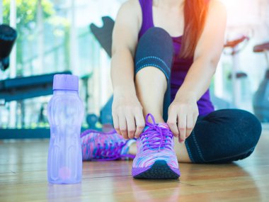 Ayakkabı - ayakkabı bağcıklarımı ipe kadın closeup çalıştırıyor. Kadın spor fitness runner backgroound fitness ekipmanları ile spor salonunda koşu için hazırlanıyor