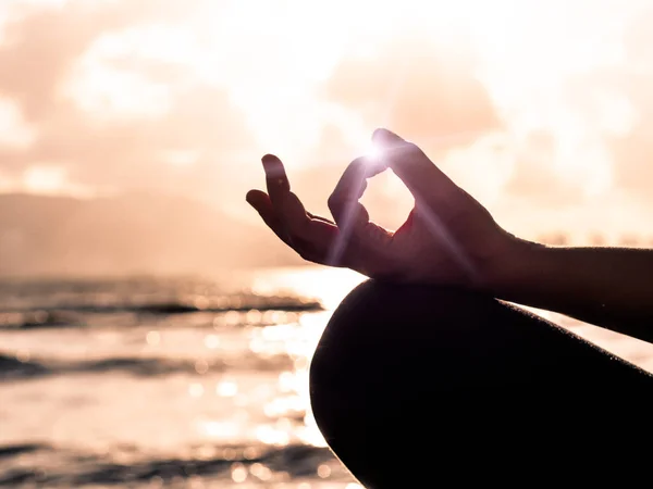 Концепція йоги. Крупним планом жінка рука практикує позу лотоса на пляжі на заході сонця — стокове фото