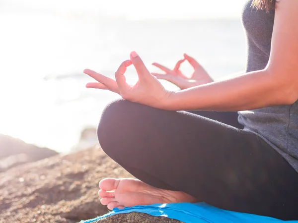 Concepto de yoga. Primeros planos de la mano de la mujer practicando la pose de loto en la playa al atardecer — Foto de Stock