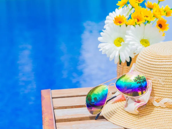 Gafas de sol con sombrero de verano y flores junto a la piscina. Vacaciones y relajación, concepto de viaje de verano . — Foto de Stock