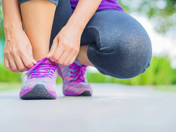 Los zapatos de correr - el primer plano de la mujer atando los cordones del zapato. Corredor de fitness deportivo femenino preparándose para correr en el fondo del jardín — Foto de Stock