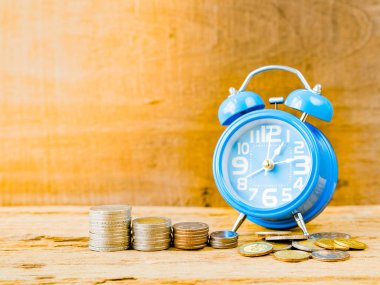 Paralar ile çalar saat ahşap zemin üzerine yığını. İşletme finansı ve zaman ve para kavramı.