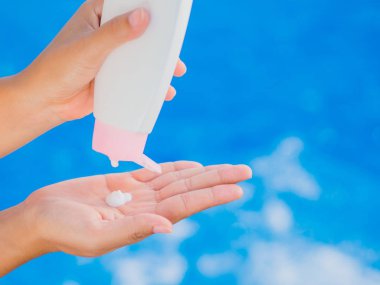 Kadın el uygulamak güneş kremi / havuz kenarında güneş kremi. Tatil ve dinlenme, yaz seyahat kavramı.