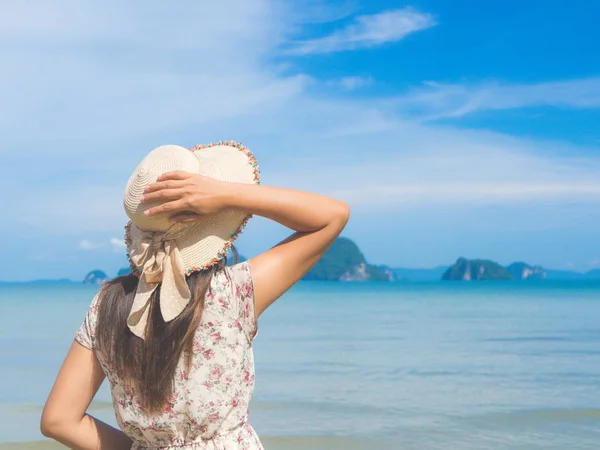 Mujer en vacaciones de verano con sombrero de paja y vestido de playa mirando la vista al océano — Foto de Stock