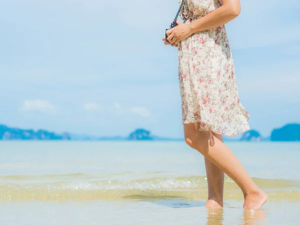 Viaje a la playa - mujer caminando en la playa de arena con cámara. Detalle de primer plano de los pies femeninos. . — Foto de Stock