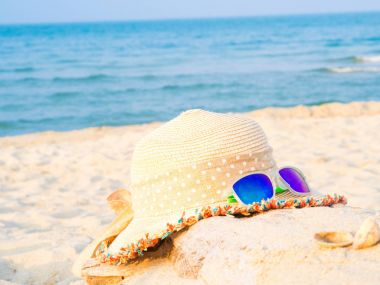 şapka ve güneş gözlüğü deniz arka plan, yaz seyahat kavramı ile sahilde