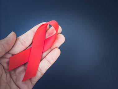 Dünya AIDS günü kavramı. Retro el kırmızı kurdele siyah arka plan ile tutarak.