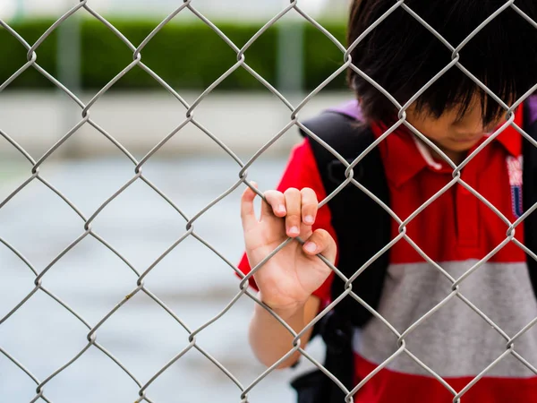 Portrait sad boy behind fence mesh netting. Emotions concept - sadness, sorrow, melancholy. — Stock Photo, Image