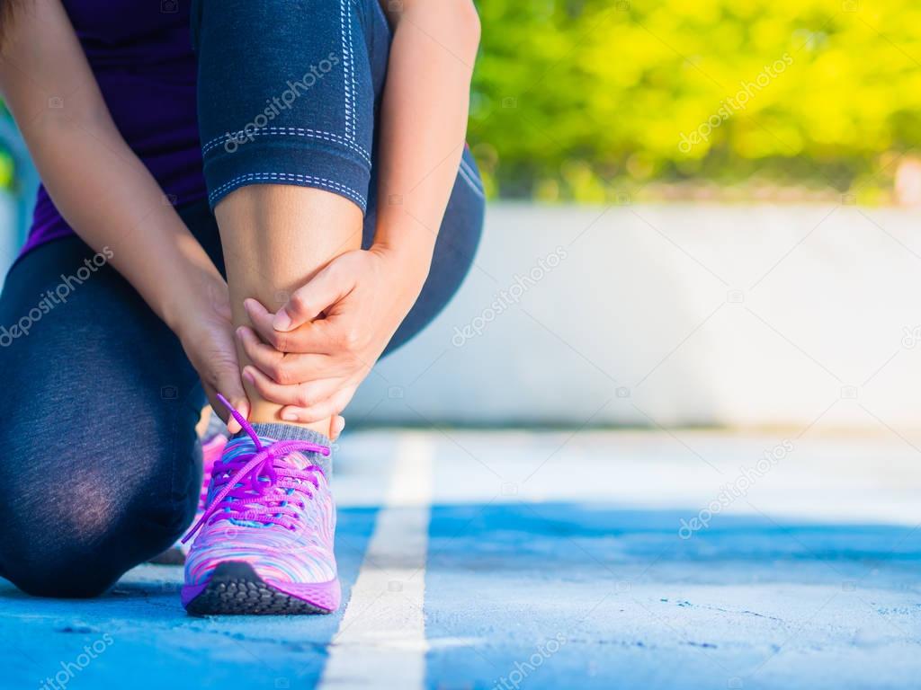 Young woman suffering from an ankle injury while exercising and running. Sport  excercise concept.