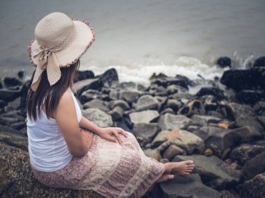 Issız bir kumsal denizde önünde oturan bir sonbahar gününde yalnız ve depresyonda kadın.