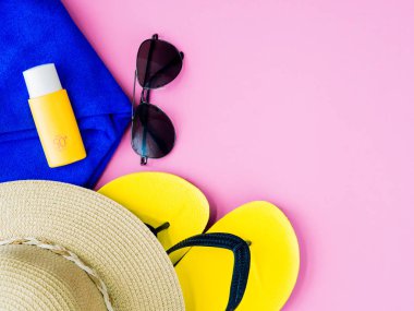 Güneş gözlüğü ile yaz şapka, Güneş Losyonu, havlu mavi ve pembe bir arka plan üzerinde floplar flip. Tatil ve dinlenme, yaz seyahat kavramı.