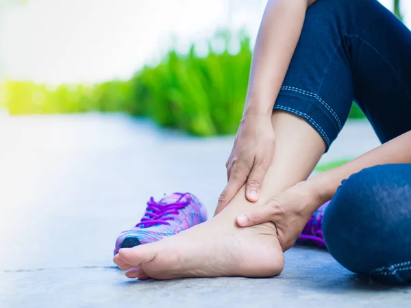 Mujer joven que sufre de una lesión en el tobillo mientras hace ejercicio y corre. Concepto de ejercicio deportivo . — Foto de Stock