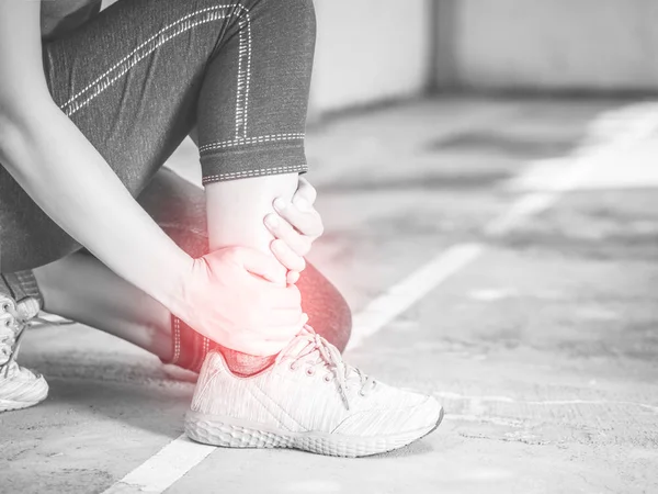 Mulher jovem preto e branco que sofre de uma lesão no tornozelo durante o exercício e corrida. Conceito de exercício desportivo . — Fotografia de Stock