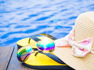 Yüzme havuzunun kenarında yaz şapka ile güneş gözlüğü ve flip floplar. Tatil ve dinlenme, yaz seyahat kavramı.