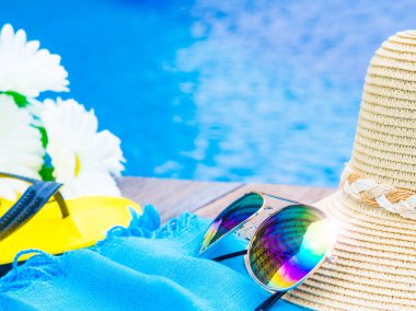 Yaz şapka ile güneş gözlüğü, flip floplar ve yüzme havuzunun kenarında çiçekler. Tatil ve dinlenme, yaz seyahat kavramı.