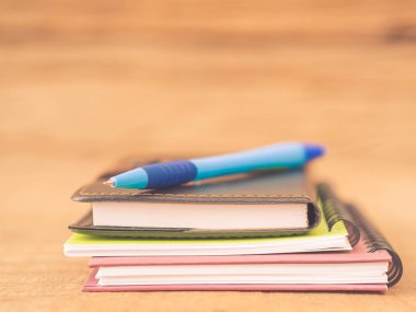 Not Defterleri ve ahşap zemin üzerine mavi kalem gibi ofis aksesuarları. Eğitim ve iş kavramı.