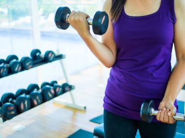 Kadın el spor salonunda fitness ekipmanları arka planda ile Halter kaldırma. Spor kavramı.